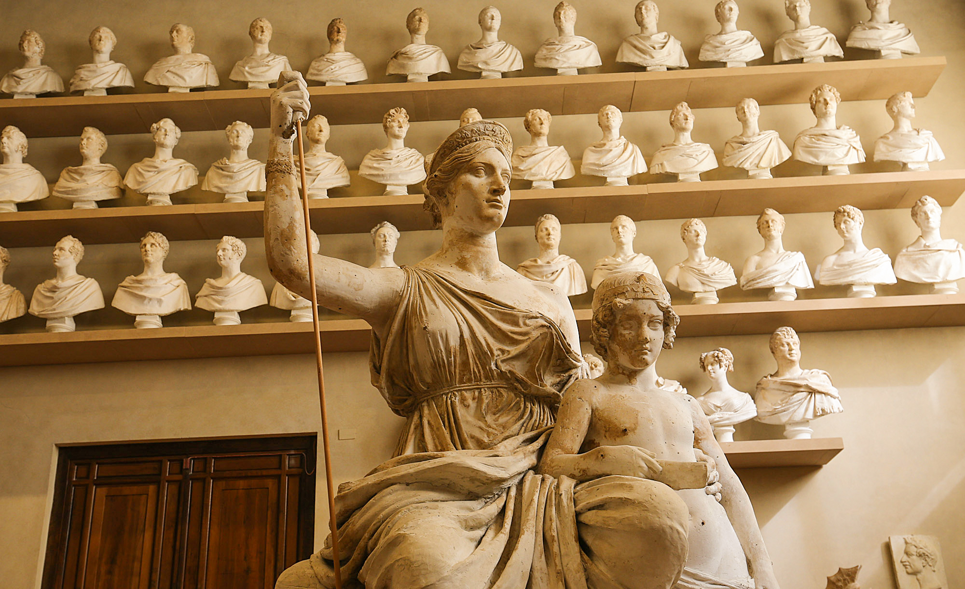 The statue is approximately 3 meters high and represents Elisa Baciocchi, wife of Napoleon Bonaparte and Grand Duchess of Tuscany. The woman is seated on a throne and wears a long dress and cloak. Her hair is gathered in a chignon and she wears a crown on her head.