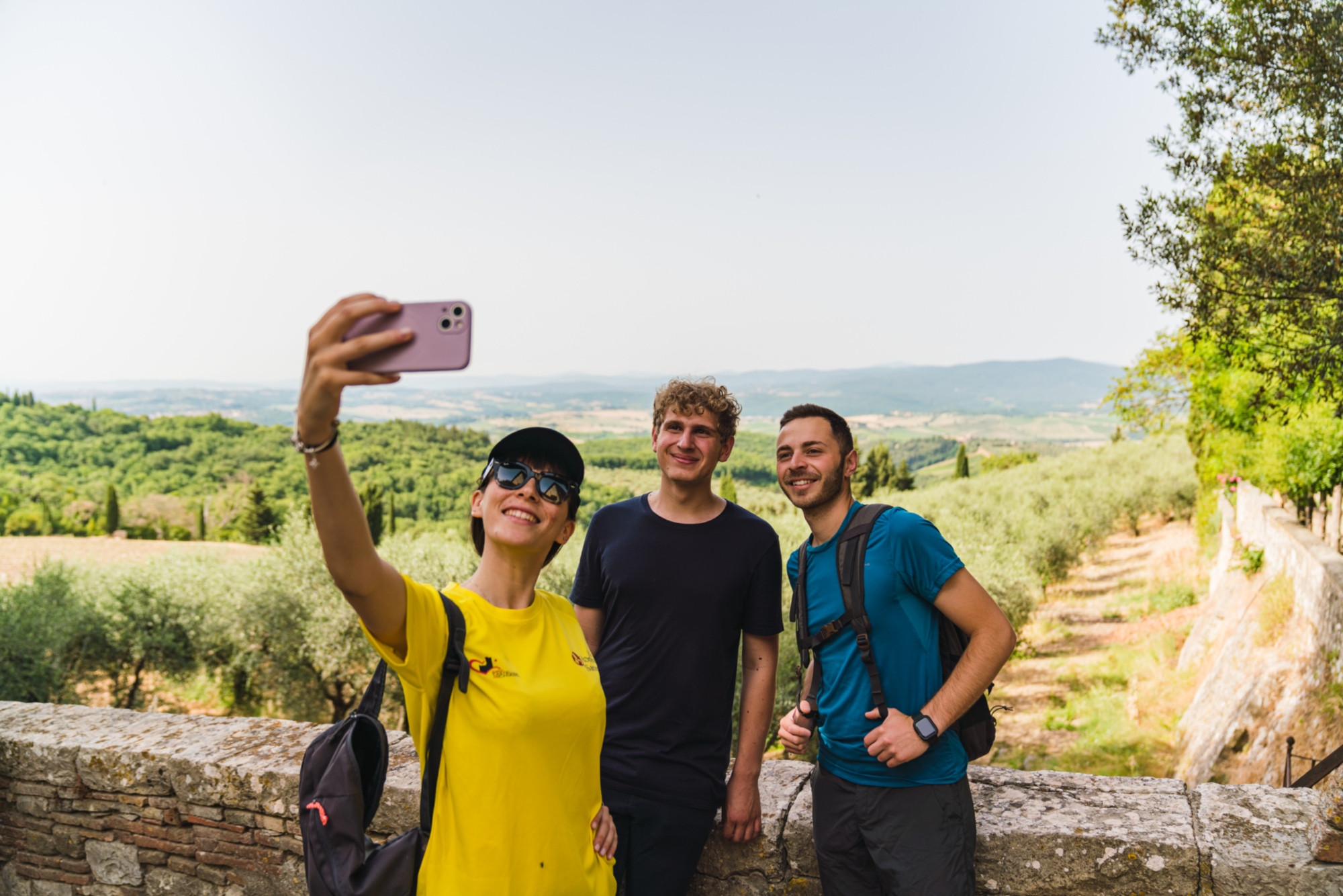 Three people take a selfie during a trek immersed in the Chianti landscape