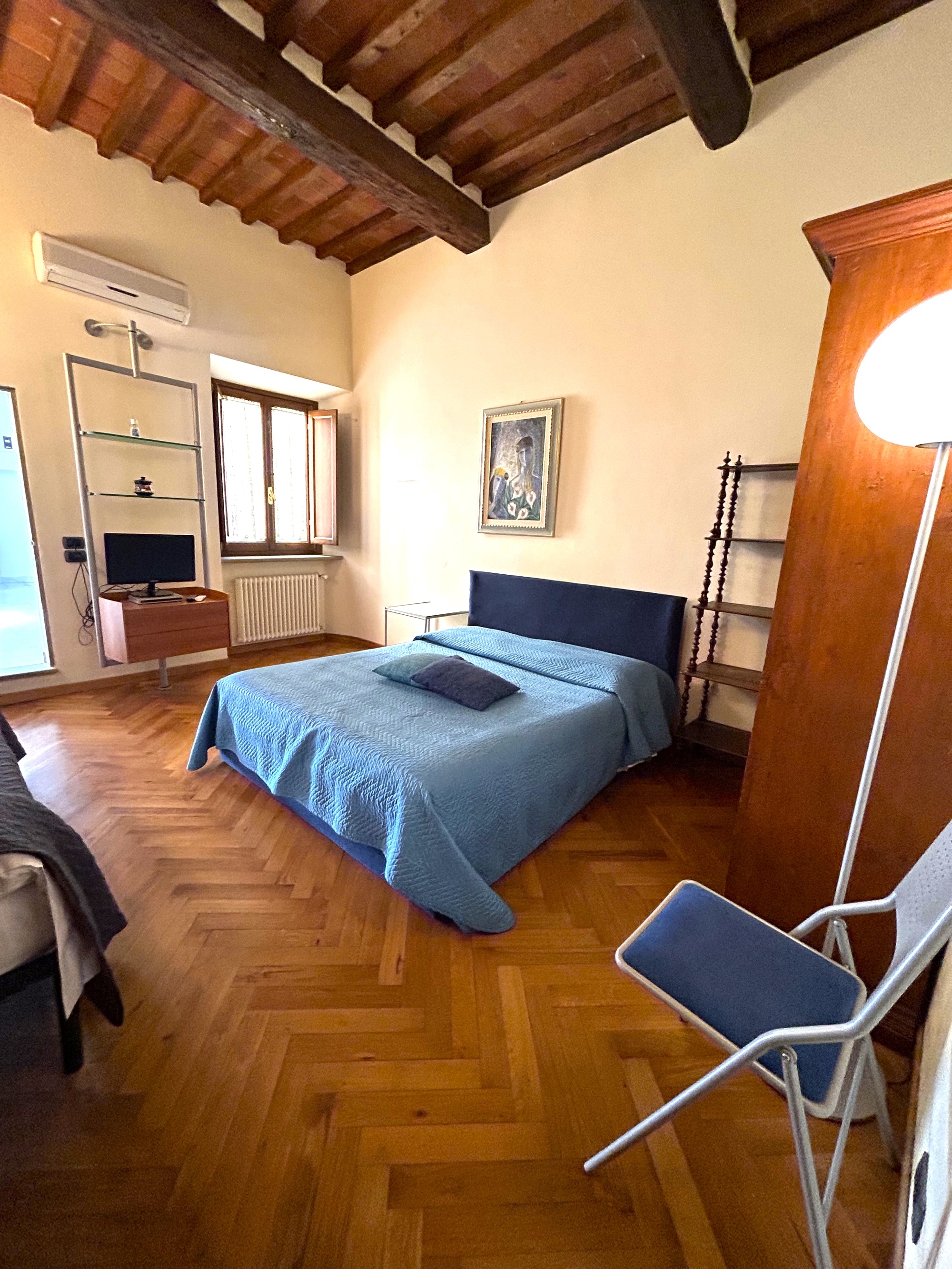 Double bedroom with herringbone parquet, exposed beams and blue furnishings