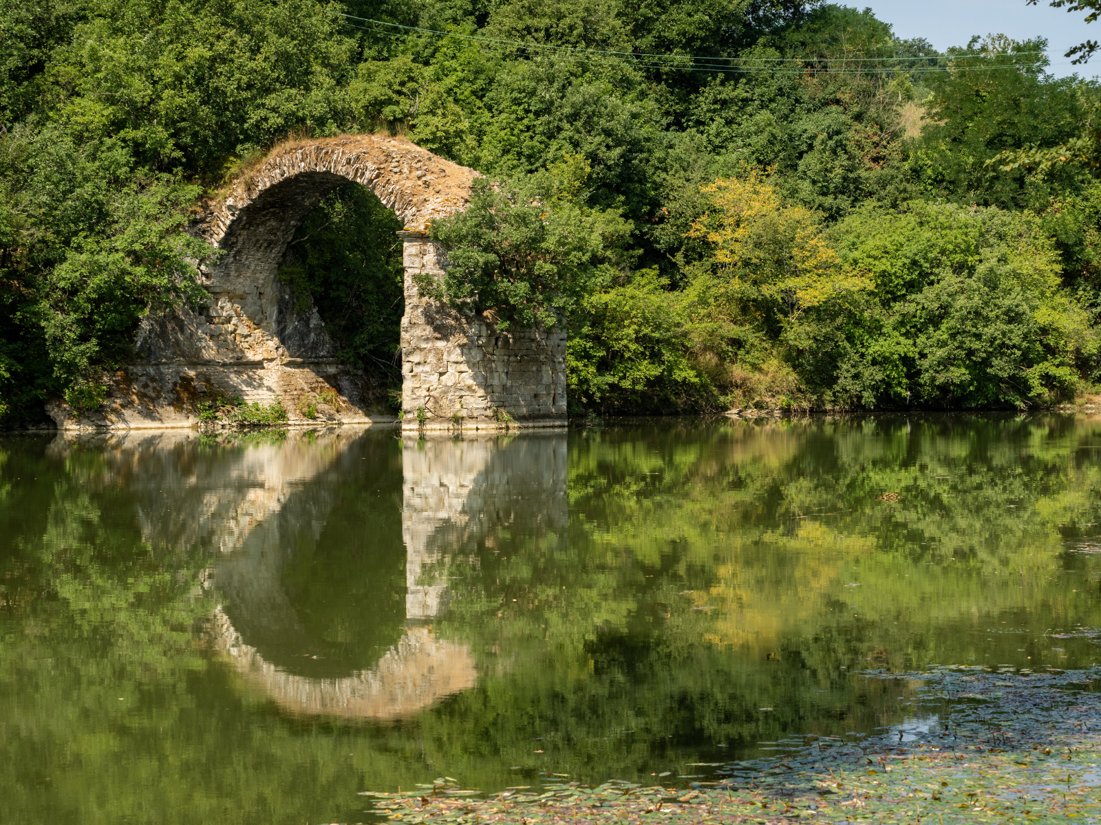 Überreste der Romito-Brücke im Valdarno-Tal, von üppiger Vegetation umgeben.