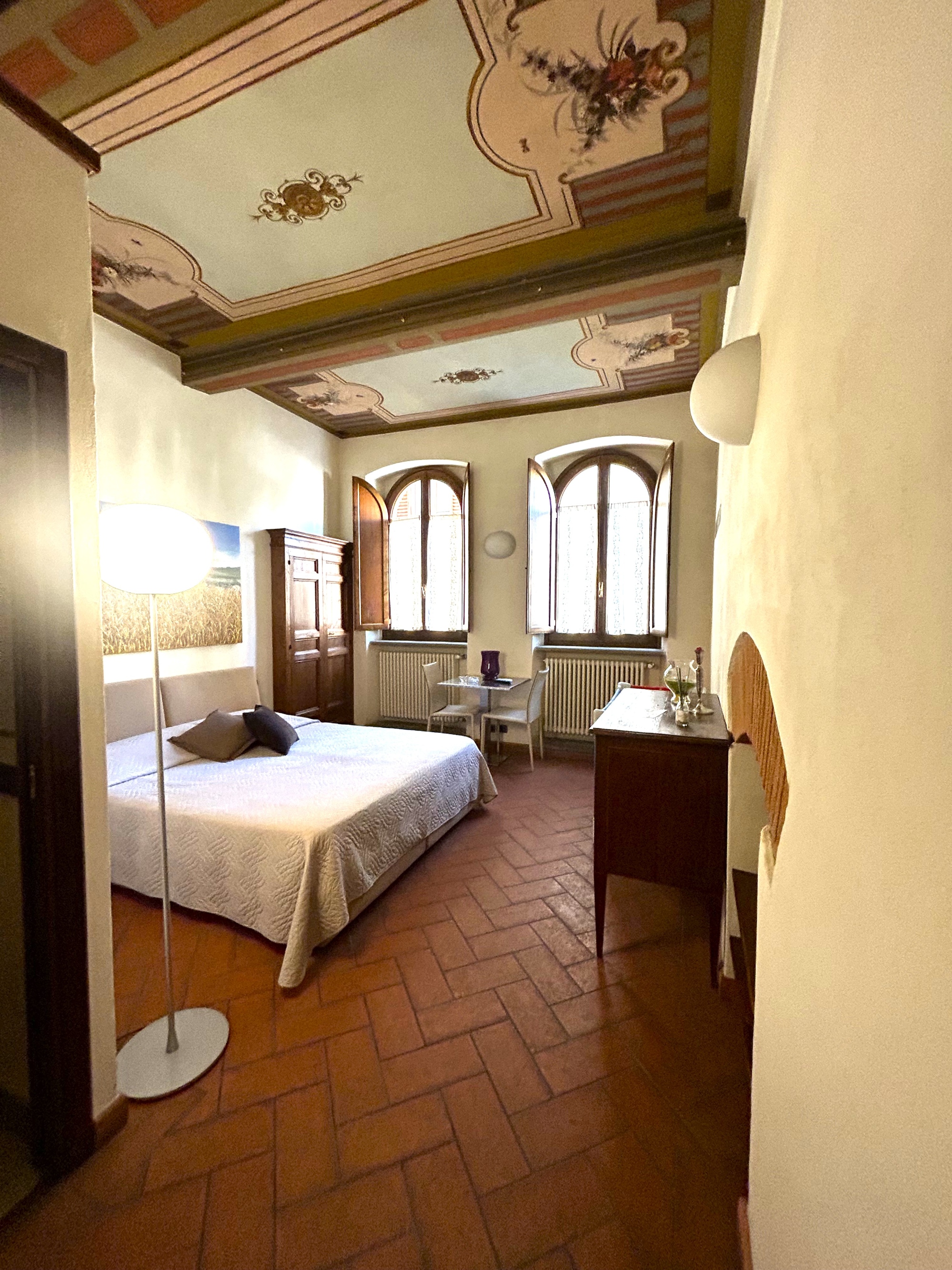 A double bedroom with frescoes on the ceiling and terracotta floors